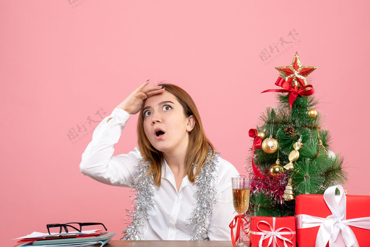 坐着女工人坐在桌子后面 粉色的圣诞礼物圣诞节工作粉色