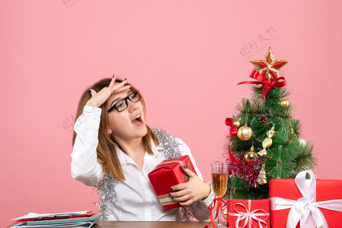 情感女工正坐在粉红色的椅子上 手里拿着圣诞礼物工作圣诞节工人