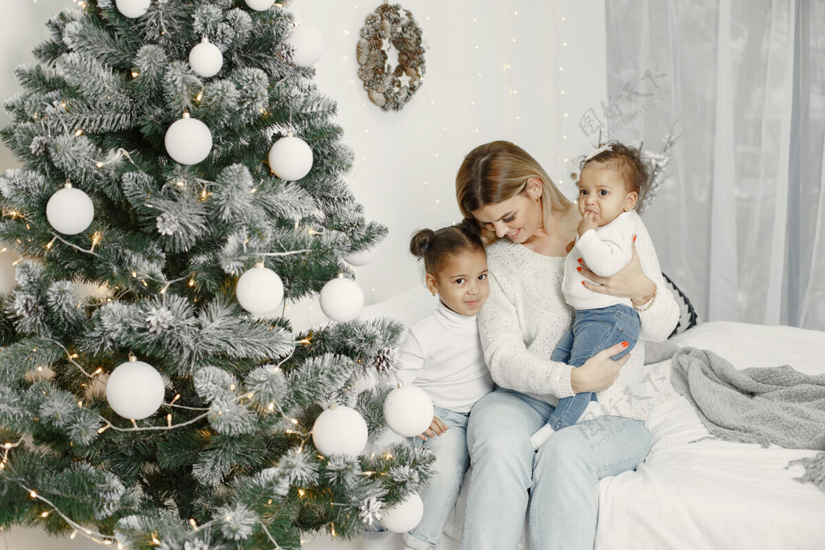亮光人们在为圣诞节做准备母亲在和女儿们玩耍一家人在节日的房间里休息孩子穿着毛衣亮光国际小