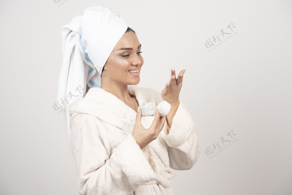 美女穿着浴衣涂面霜的年轻女人人女性治疗