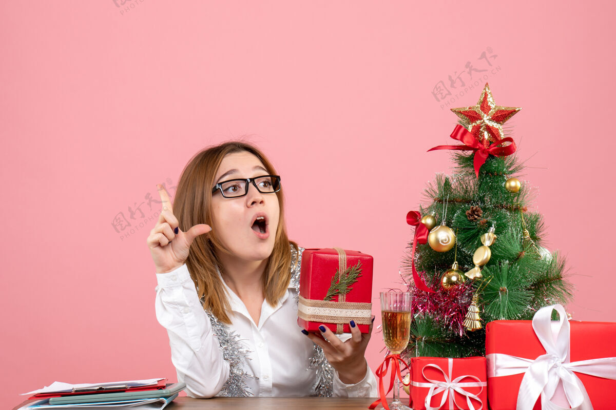 粉色女工正坐在粉红色的椅子上 手里拿着圣诞礼物情感礼物圣诞节