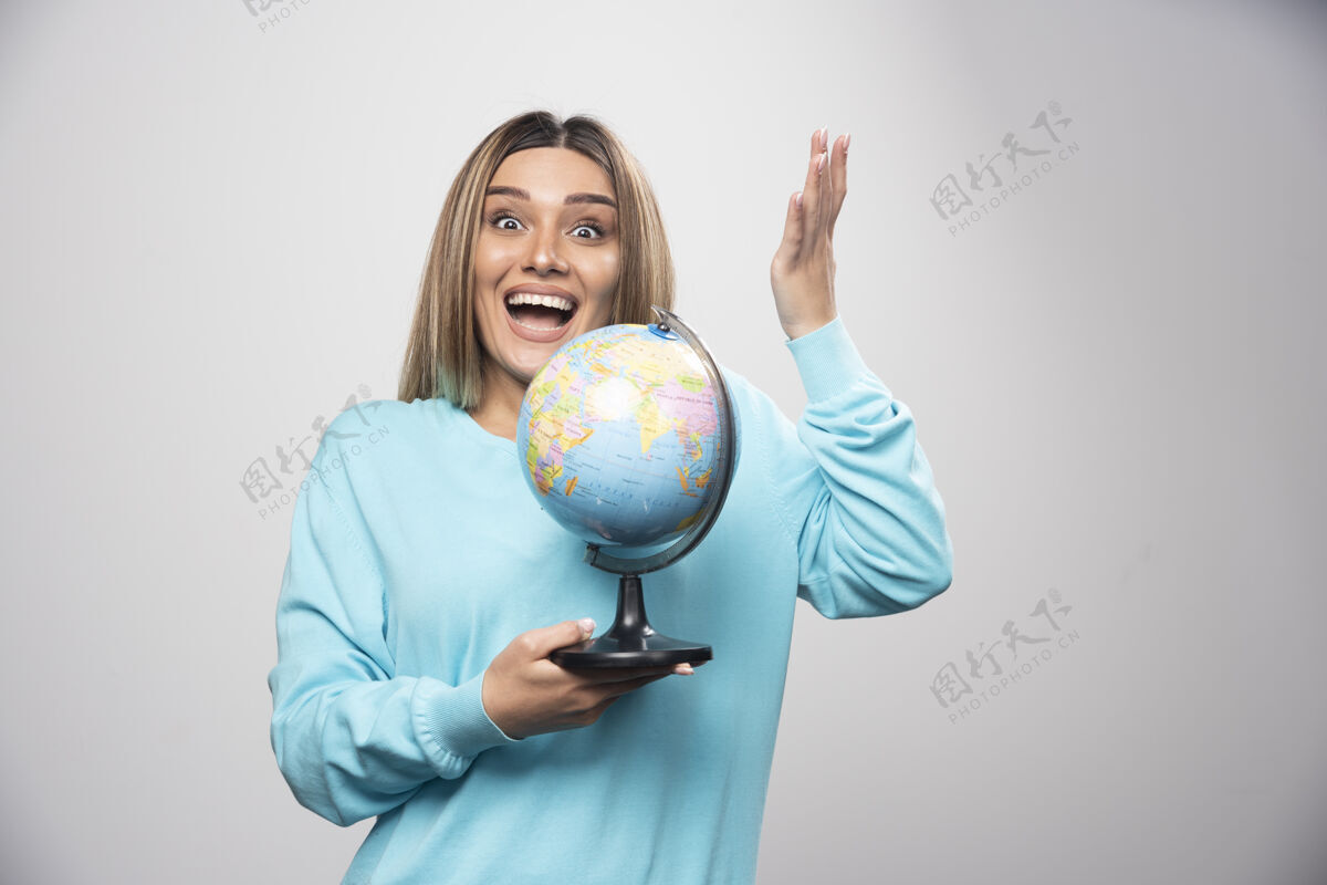 地球穿着蓝色运动衫的金发女孩拿着一个地球仪 猜着地点 玩得很开心旅行休闲微笑
