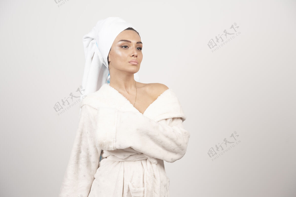 成人穿着白色浴袍的漂亮年轻女子在白墙上摆姿势女性治疗水疗