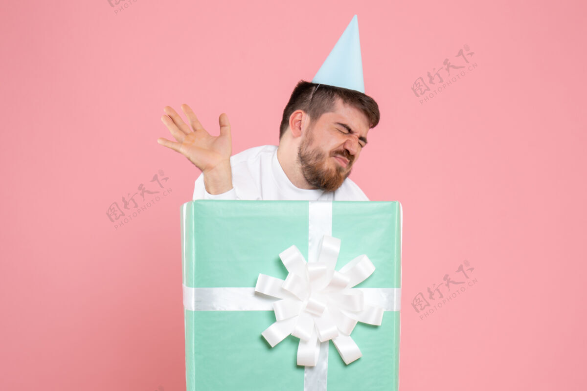 情感正面图：年轻人站在盒子里 在粉红色的墙上感到疲倦年轻节日圣诞节