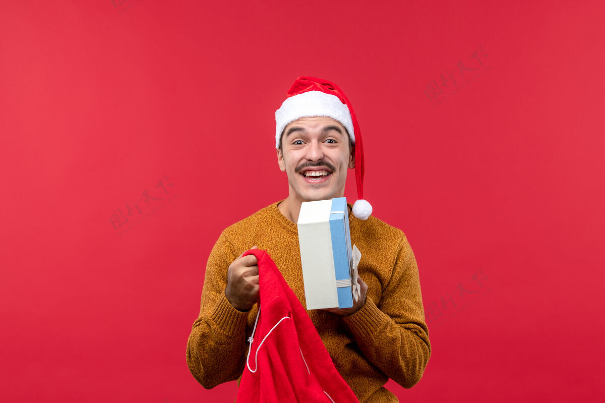 礼物年轻人从红墙包里拿出礼物的正面图包年轻男性男人