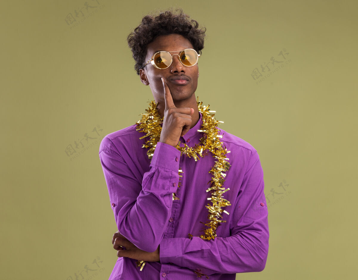 年轻体贴的非洲裔美国年轻人戴着眼镜 脖子上戴着金箔花环 看着橄榄绿背景上孤立的侧脸脖子橄榄侧面
