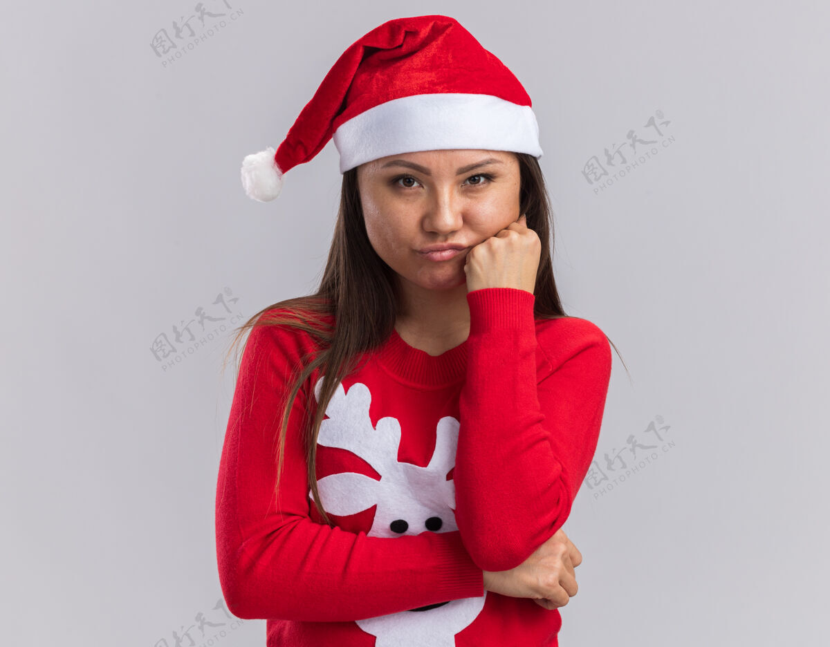 年轻悲伤的亚洲女孩戴着圣诞帽 手放在脸颊上 戴着毛衣 背景是白色的毛衣悲伤脸颊