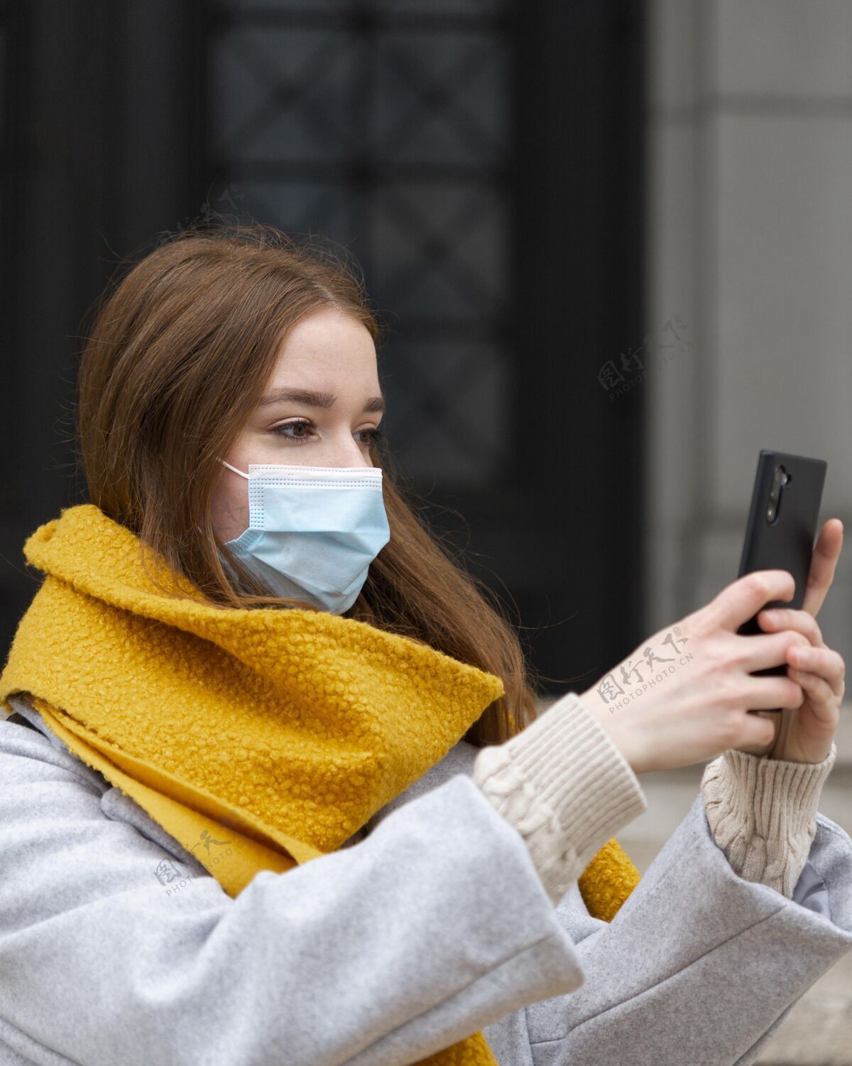 病毒戴着医用面罩的女士用智能手机拍照的侧视图智能手机预防面罩