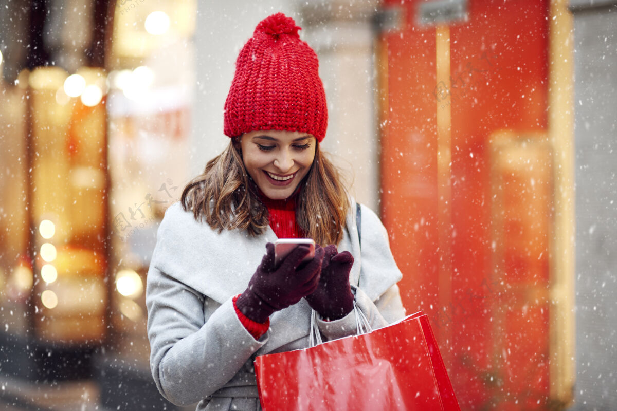 优雅美丽的女人在冬天购物时用手机包微笑针织