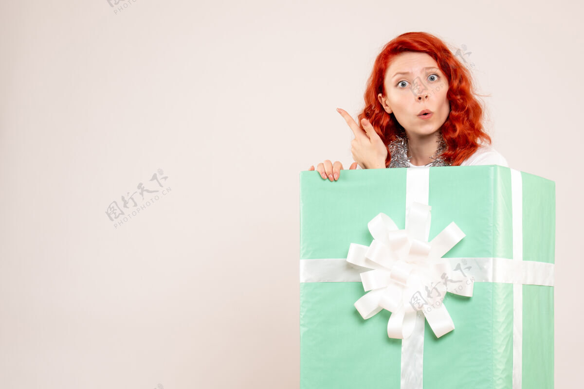 圣诞节隐藏在白墙上的年轻女子的正面视图节日礼品盒庆祝