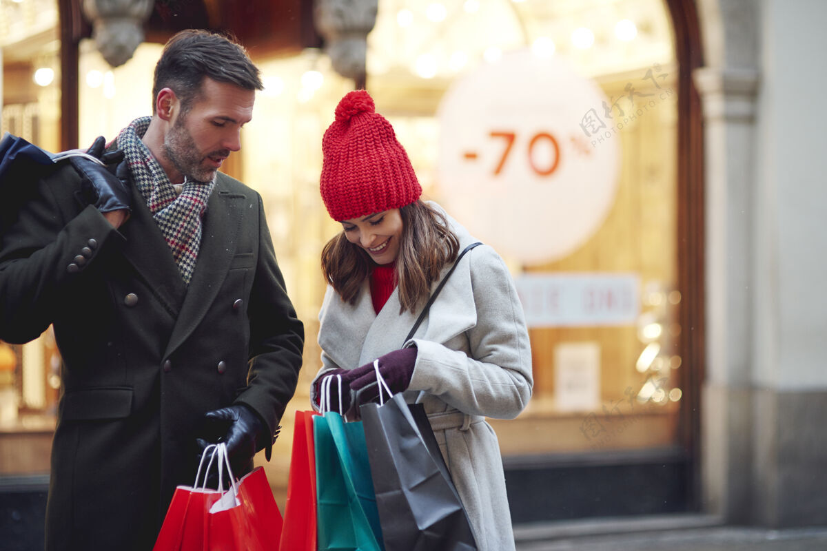 微笑在冬天的时候 情侣们在购物袋旁购买编织享受