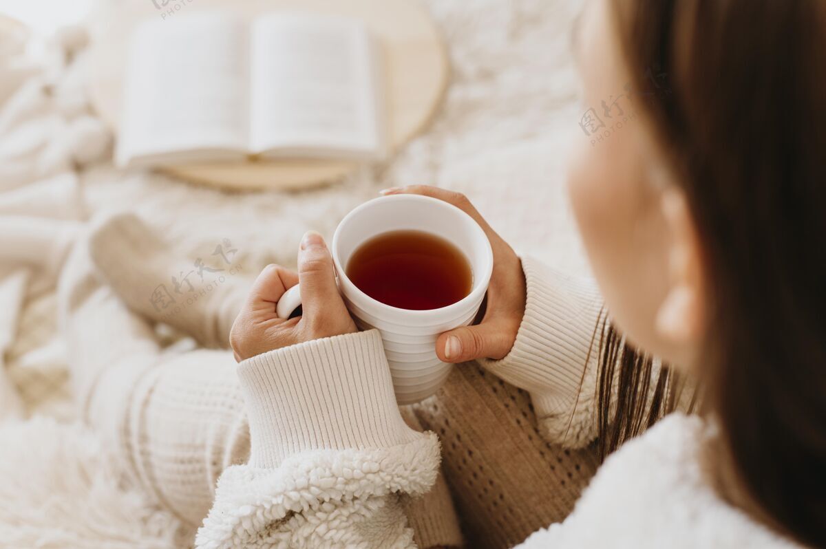 愉快年轻女子一边喝茶一边享受寒假放松室内舒适