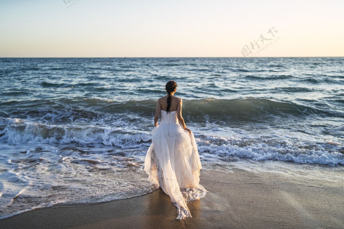 新娘黑发白人新娘穿着白色婚纱走向大海女性黑发自然