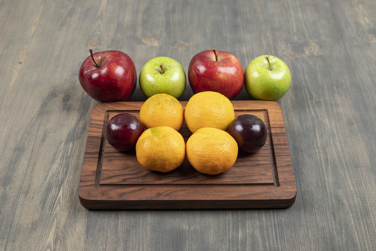 新鲜多汁的红苹果 李子和橘子放在木砧板上高质量的照片健康切茶点