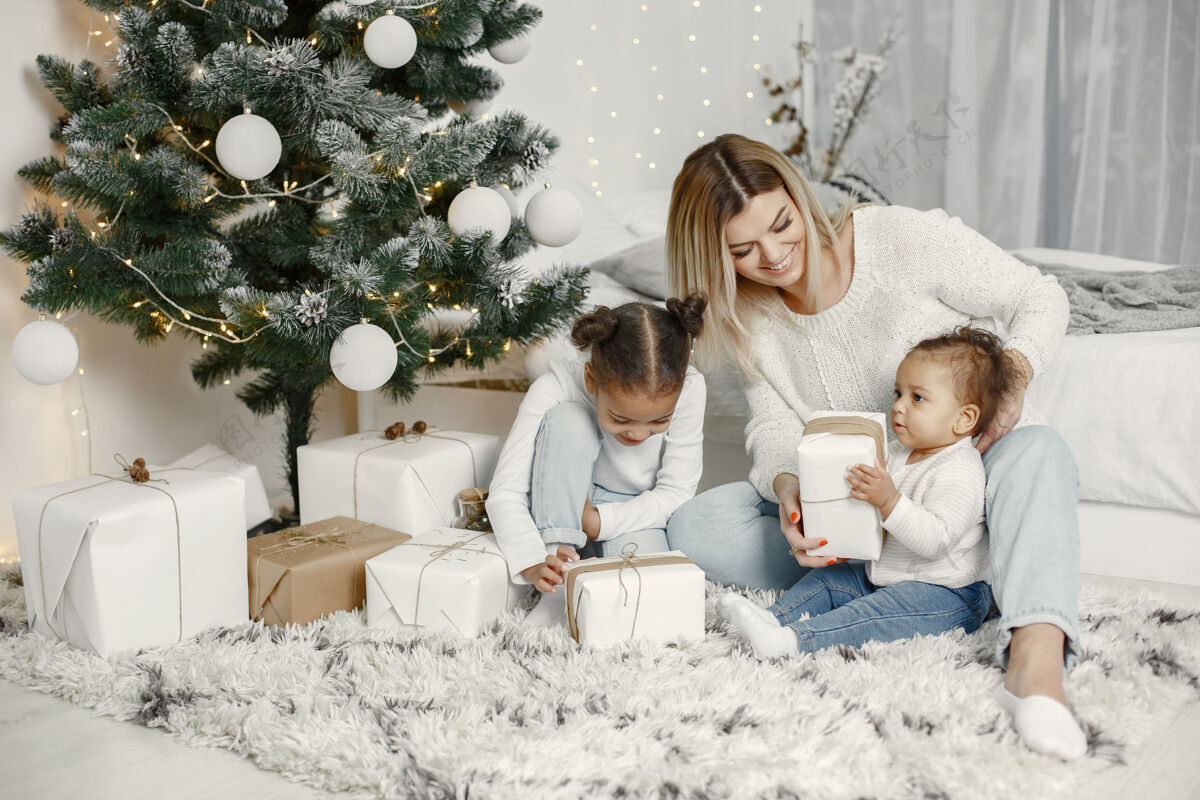 给人们在为圣诞节做准备母亲在和女儿们玩耍一家人在节日的房间里休息孩子穿着毛衣孩子亮光肖像
