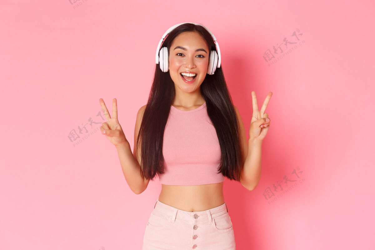 无线一个戴着耳机听音乐的富有表情的年轻女子肖像日语时尚