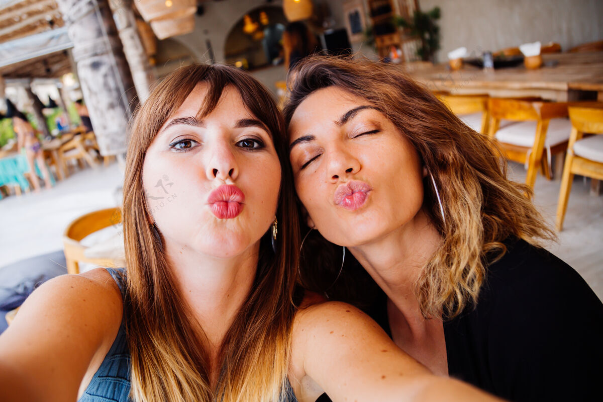 制作两位自然妆容 短发的欧洲白人女性朋友在夏日咖啡馆自拍年轻友谊照片