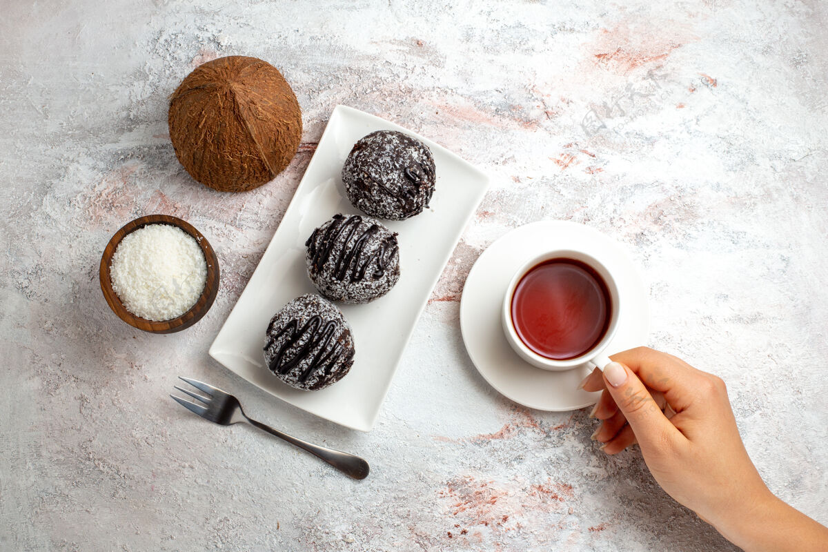饼干俯瞰巧克力蛋糕与一杯茶和椰子在白色表面巧克力蛋糕饼干糖甜饼干蛋糕浓缩咖啡早餐