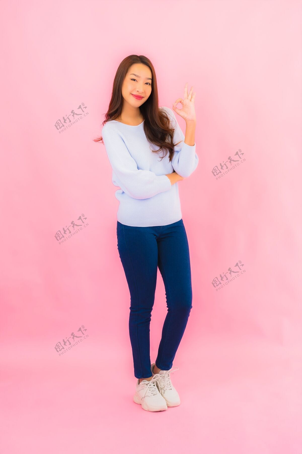 中国人美丽的亚洲年轻女子在粉红色的隔离墙上微笑韩语表情幸福