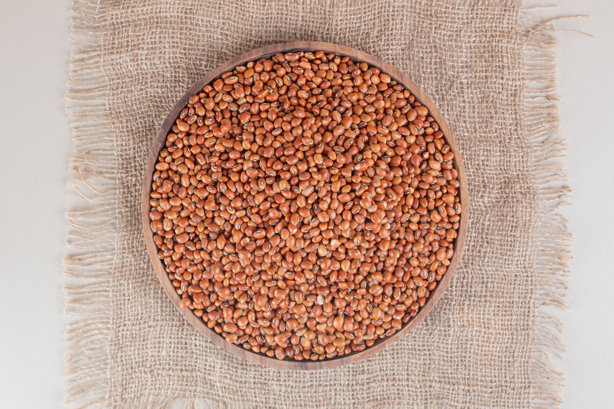 生物把生的棕色豆子放在混凝土上的木盘上板有机成分