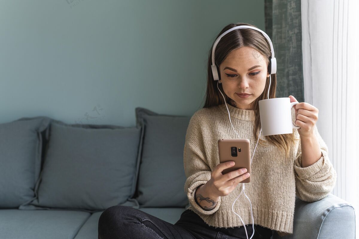 隔离流感大流行期间 在家喝咖啡时使用耳机和智能手机的妇女社会距离家庭病毒