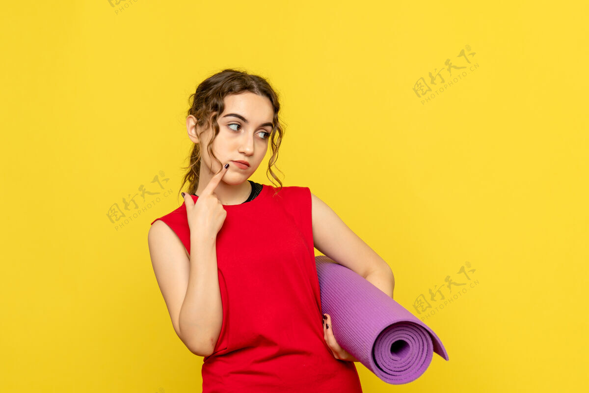 人黄色墙上拿着紫色地毯的年轻女子的正视图磁盘骑师女人年轻女性