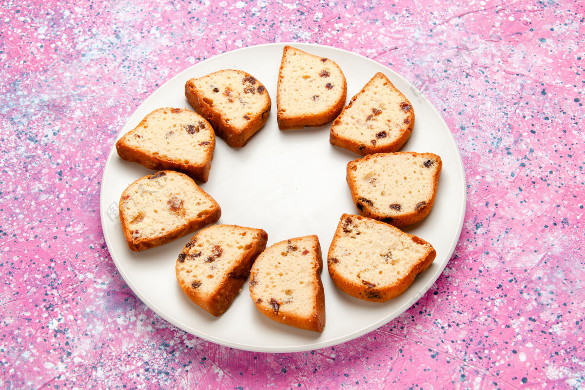 烘焙半俯视图蛋糕片与葡萄干内盘粉红色表面蛋糕烤甜饼干彩色派糖饼干小吃早餐半顶