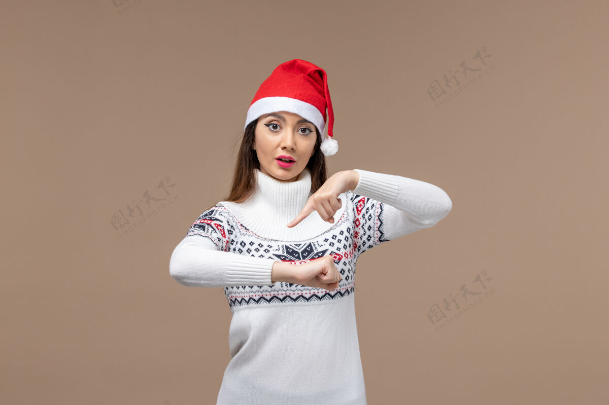 快乐前视图年轻女性检查时间在棕色背景情感圣诞假期成人帽子年轻