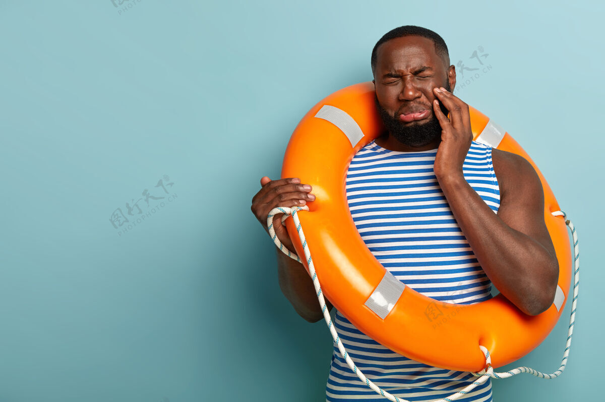 保护者心烦意乱的黑皮男人脸上露出悲伤的表情 闭上眼睛 提着救生圈安全地游泳非洲紧急保护