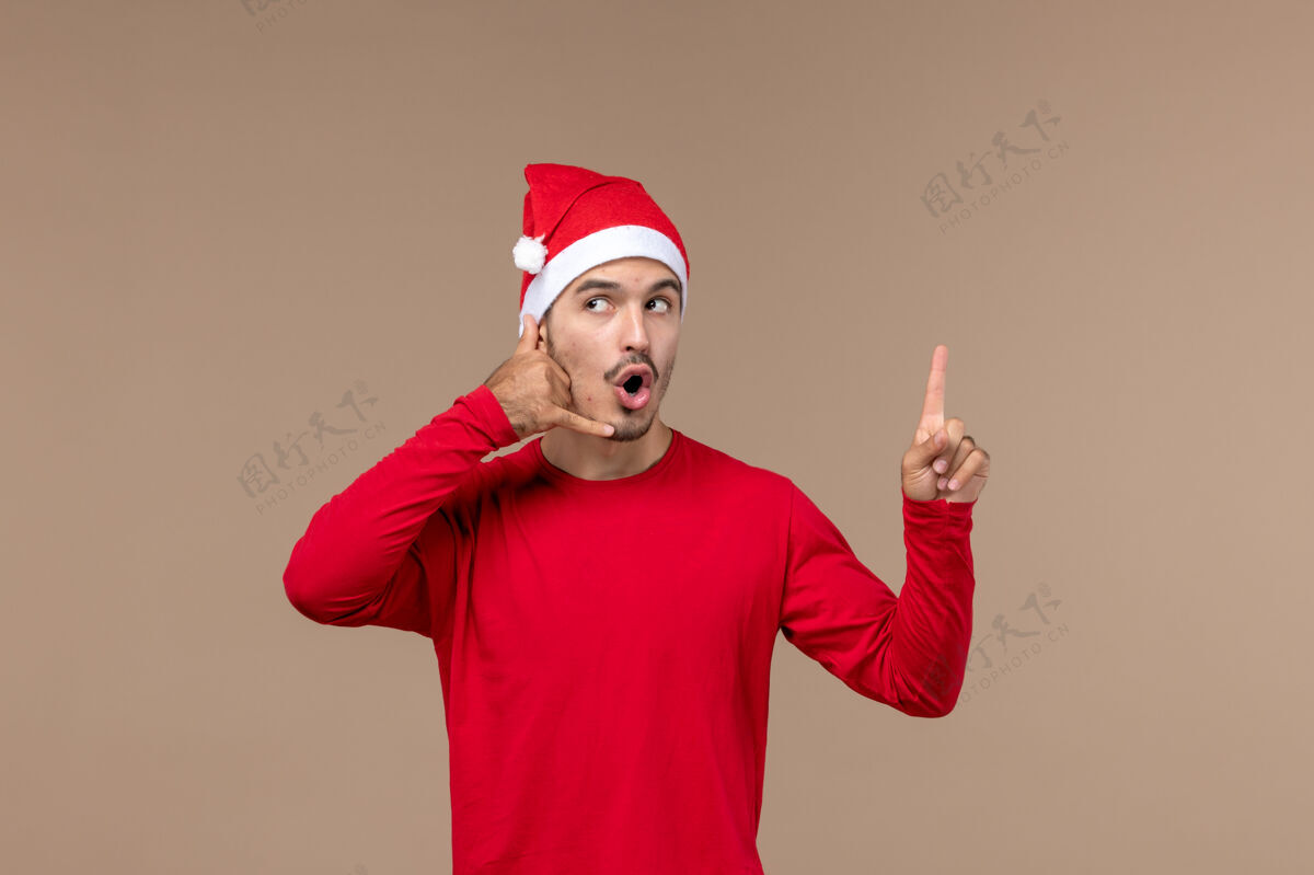 帽子正面图棕色背景上表情好奇的年轻男性圣诞情感节日男性微笑人节日