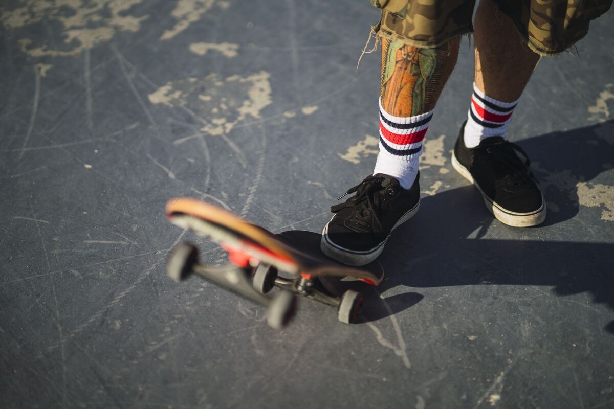 休闲年轻男子在公园里玩滑板玩不同的把戏光城市男性