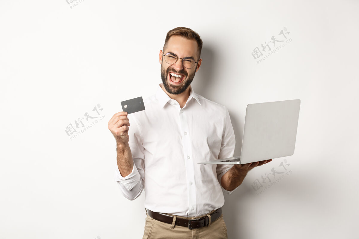 员工网上购物帅哥出示信用卡 用笔记本电脑在网上点菜 站着男人信用卡衬衫