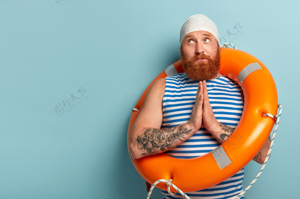 水手希望英俊的男游泳者双手合十 祈祷安全游泳 在度假胜地重现 穿水手背心摆姿势T恤胡茬