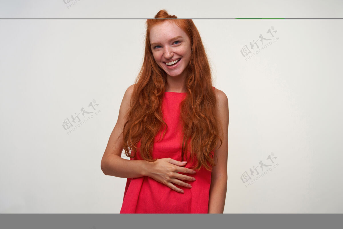 微笑摄影棚照片：迷人的年轻女性 卷发 身穿粉色连衣裙 站在白色背景上 手掌放在身上 对着镜头积极微笑手掌身体肖像