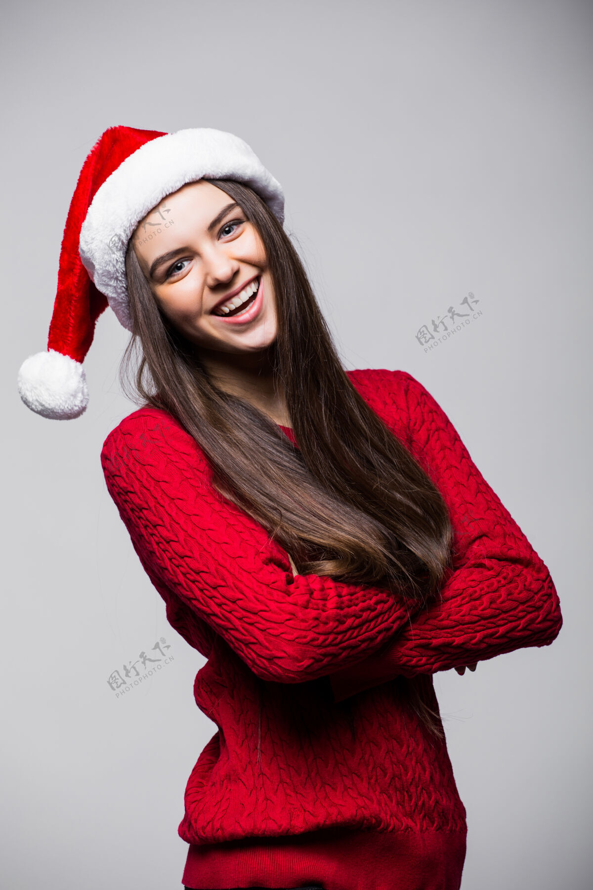 女人可爱的年轻白人妇女戴着圣诞帽和手套对着浅灰色的墙壁微笑圣诞节和新年的概念复制空间可用年轻圣诞老人快乐