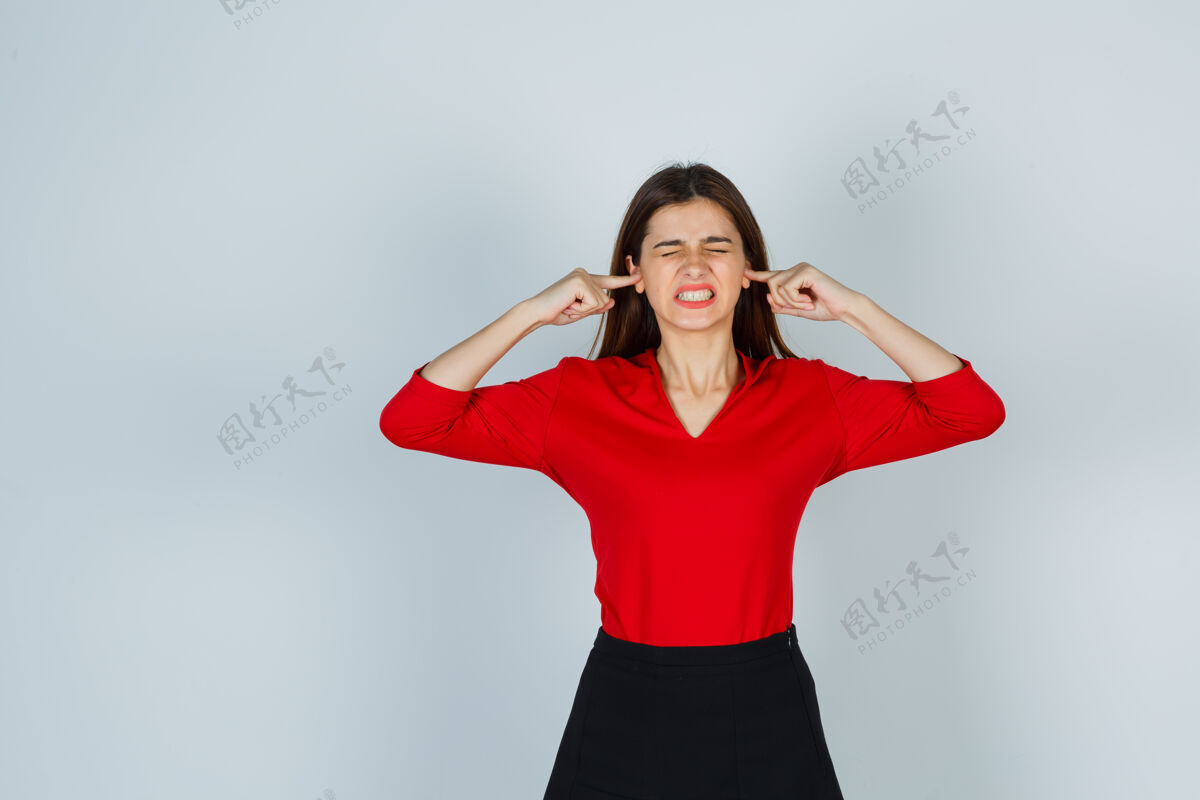 衬衫穿着红衬衫 裙子 用手指堵住耳朵的年轻女士看起来很生气人情绪化年轻