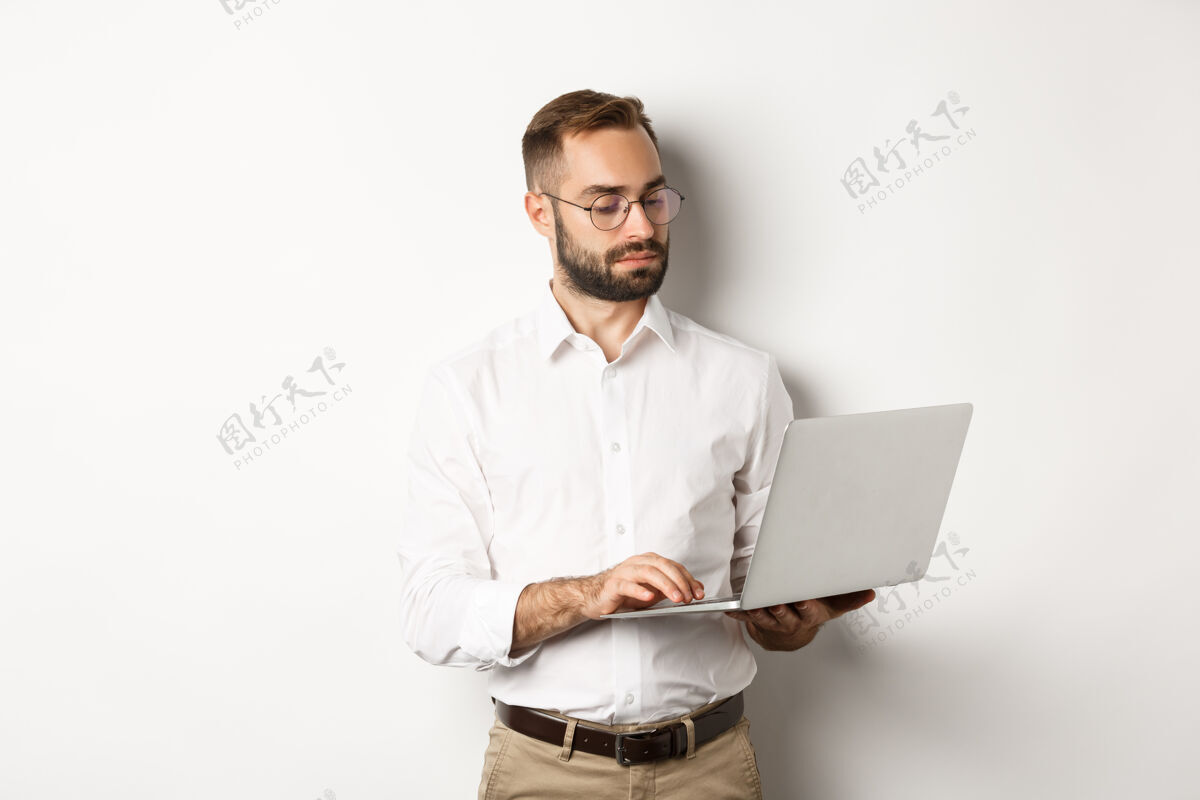 使用认真的经理在笔记本电脑上工作 站着老板办公室时髦