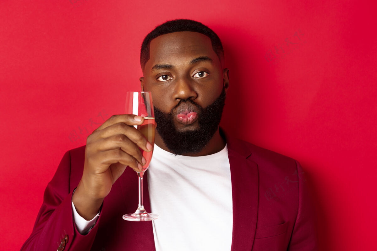 聚会特写镜头中有趣的黑人男子品尝香槟从玻璃 看起来愚蠢和嘴唇皱褶胡须肖像正式