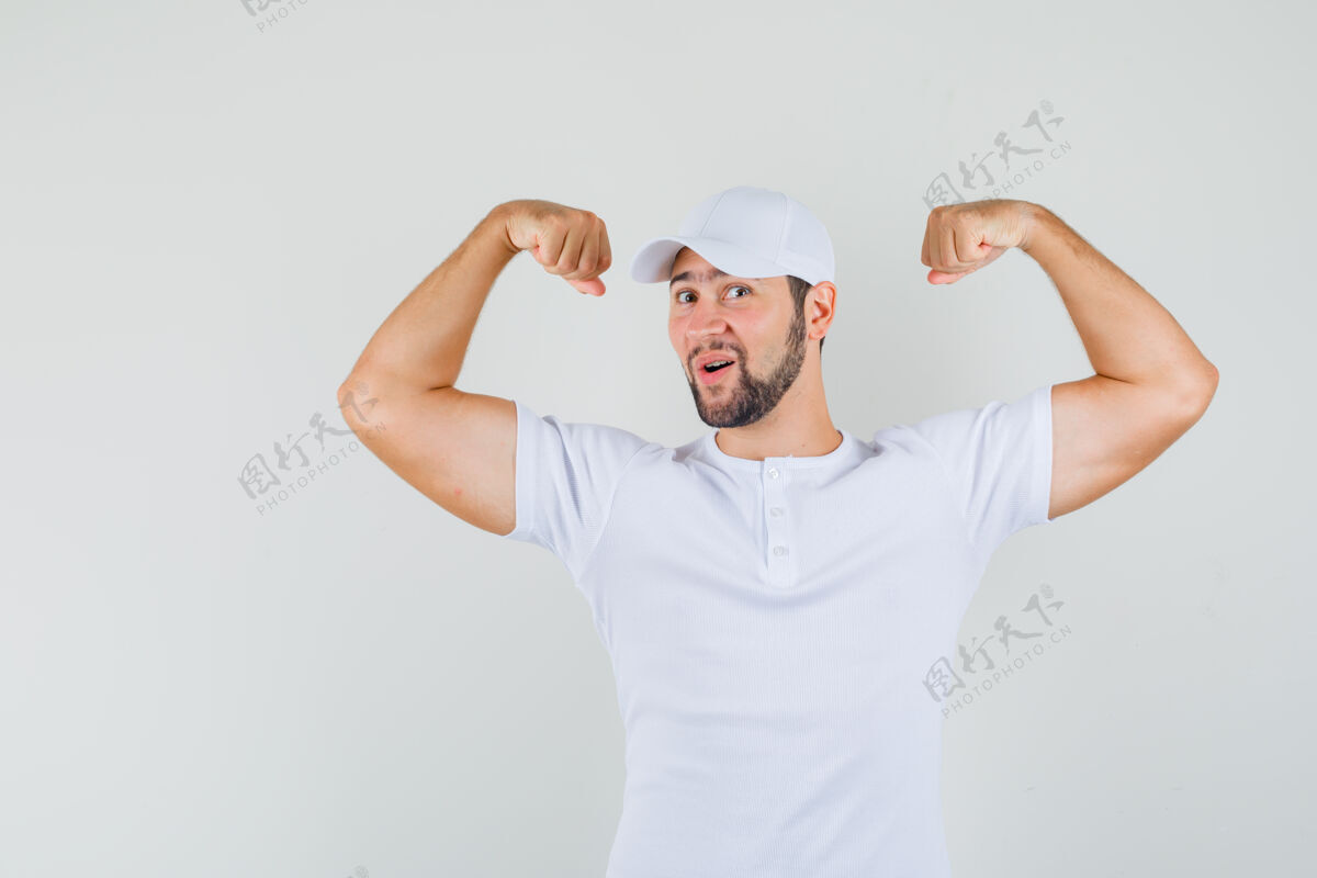 肖像年轻人展示他的手臂肌肉在t恤 帽子和看起来很好 前视图成人手势年轻