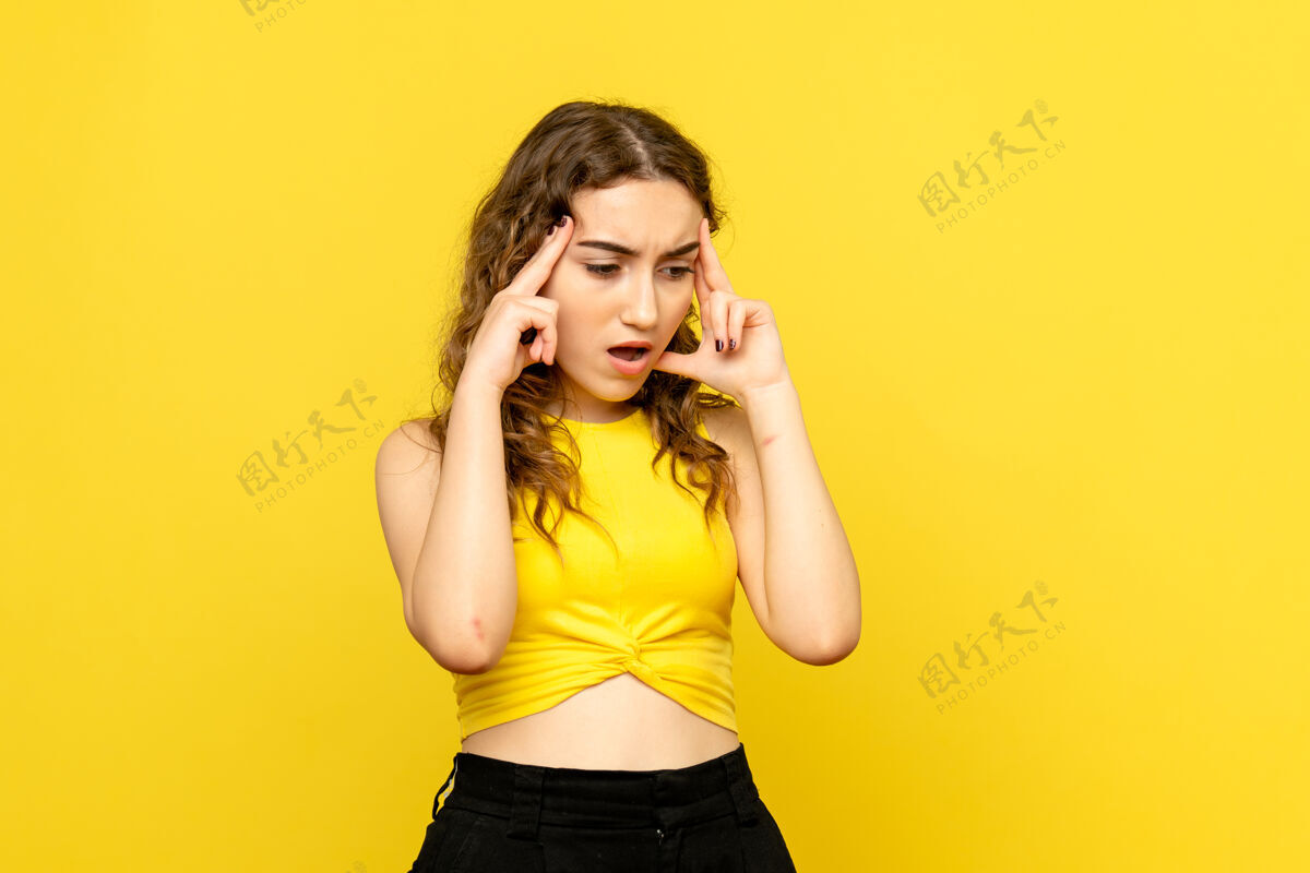 观点黄色墙壁上有思考表情的年轻女孩的正面视图模型年轻女孩前面