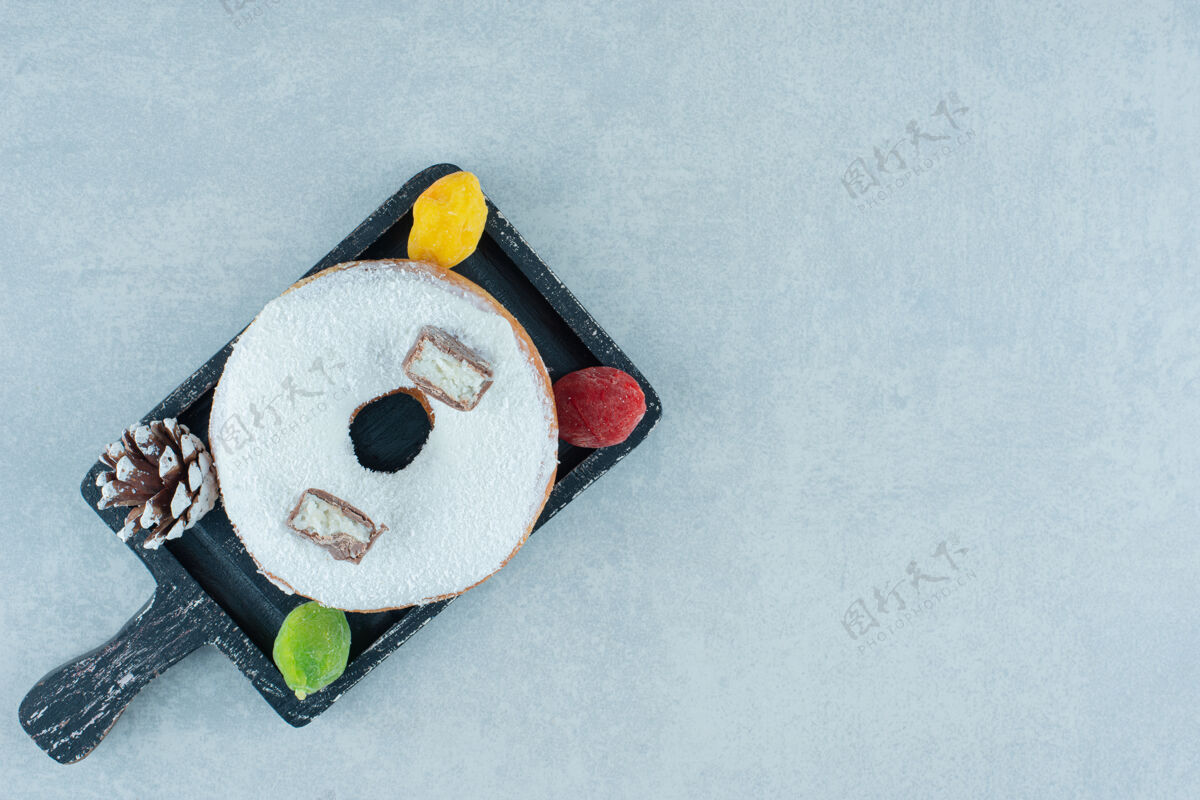 顶部视图在大理石上的黑色托盘上放一个果酱 松果和一个甜甜圈顶部圆锥体视图