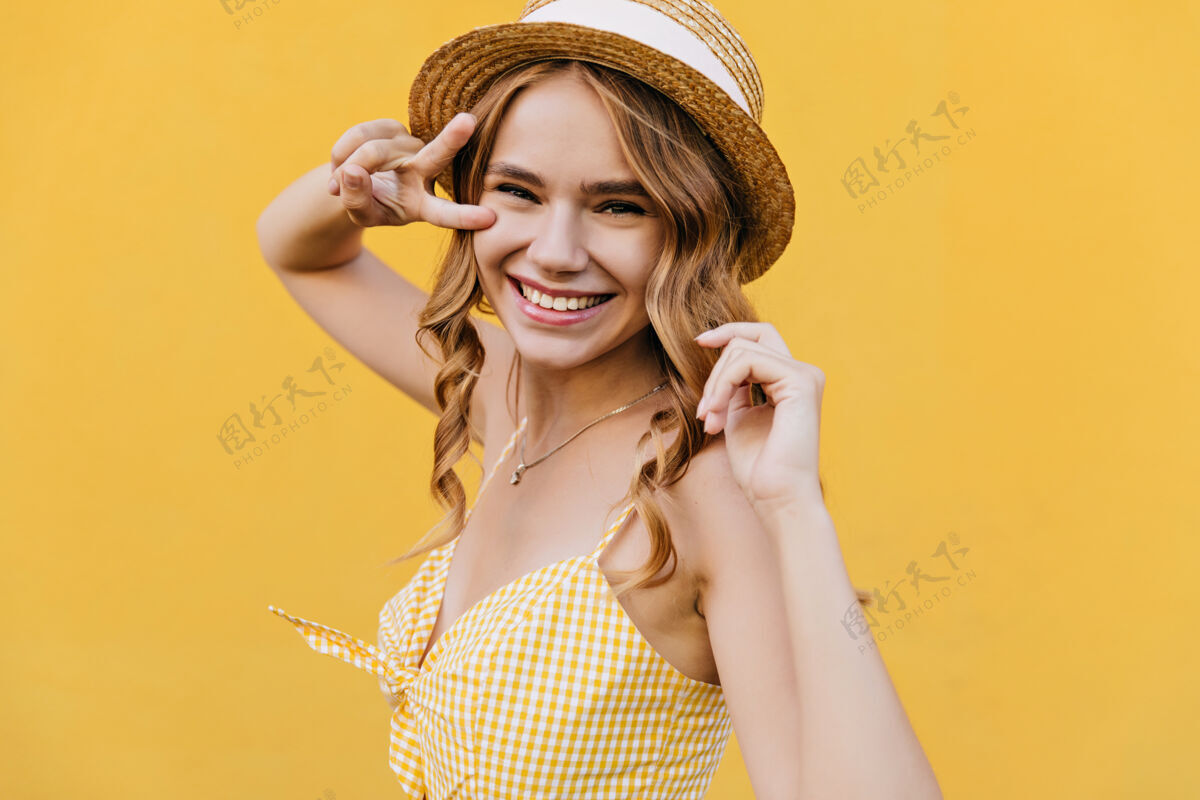 笑戴着帽子的浅棕色卷发女人微笑着室内拍摄的灵感女模特穿着格子黄色服装浪漫苗条时尚