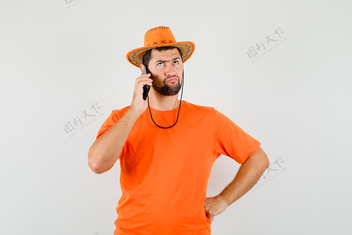 成人年轻人穿着橘色t恤 戴着帽子 神情犹豫不决 正对着手机说话人衬衫男人