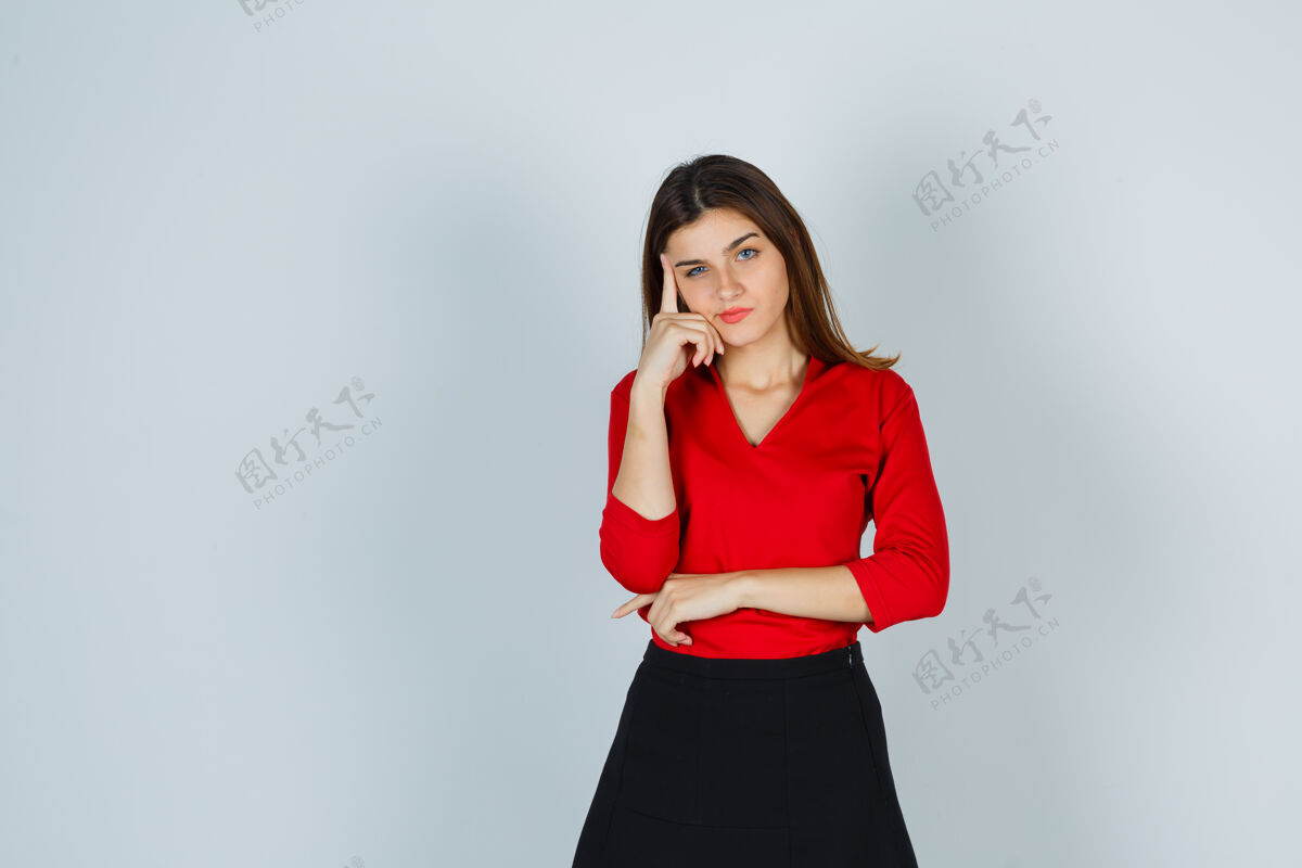 衬衫年轻的女士站在思考的姿势在红色衬衫 裙子和期待沉思美丽休闲孤独