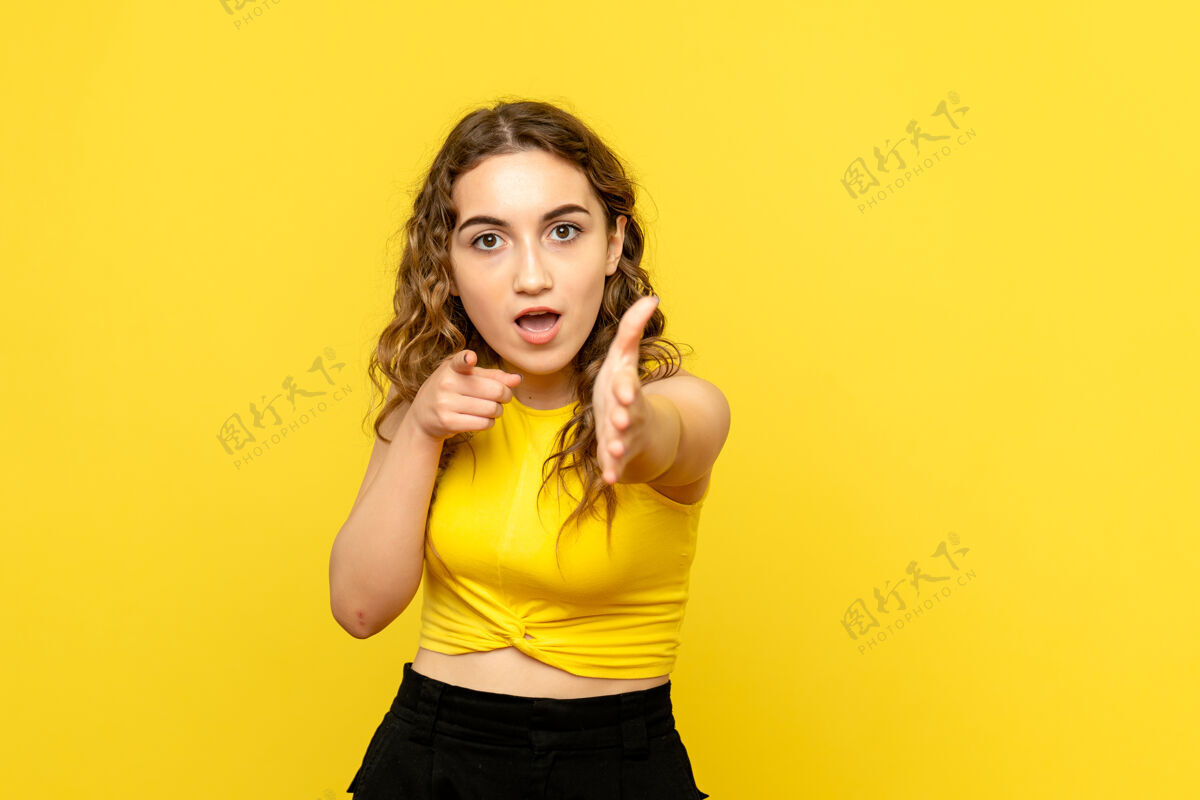 肖像年轻女子试图在黄色墙上握手的正面图手头发漂亮
