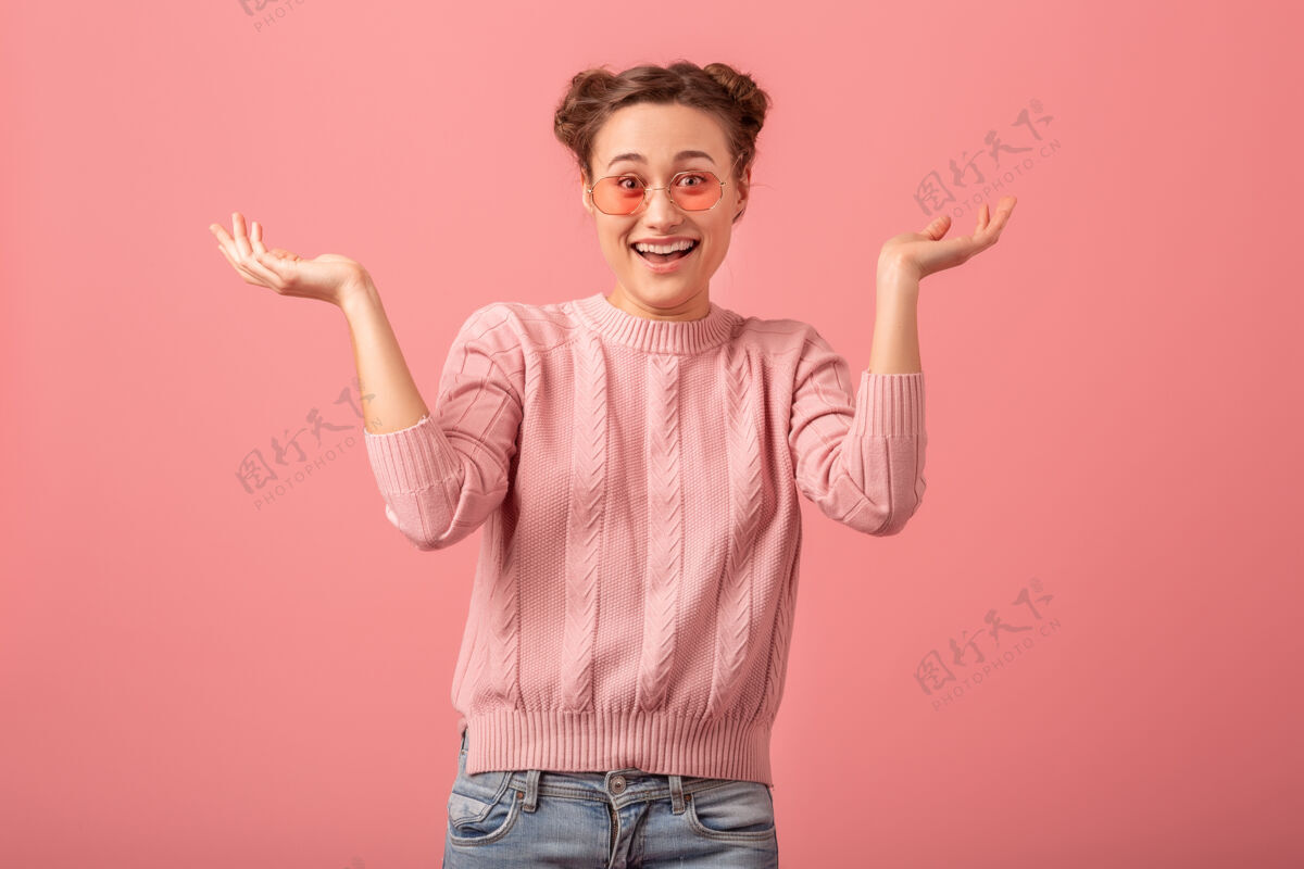 女人一个年轻漂亮的笑脸女人 穿着粉色毛衣 戴着墨镜 在粉色工作室的背景下与世隔绝肖像女性微笑