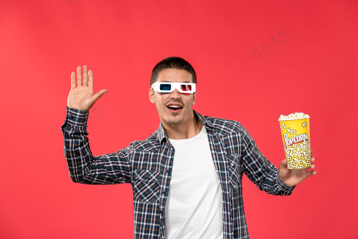 年轻男性正面图戴着d墨镜的年轻男性手持爆米花包在浅红色的墙上看男性电影浅红色包装肖像