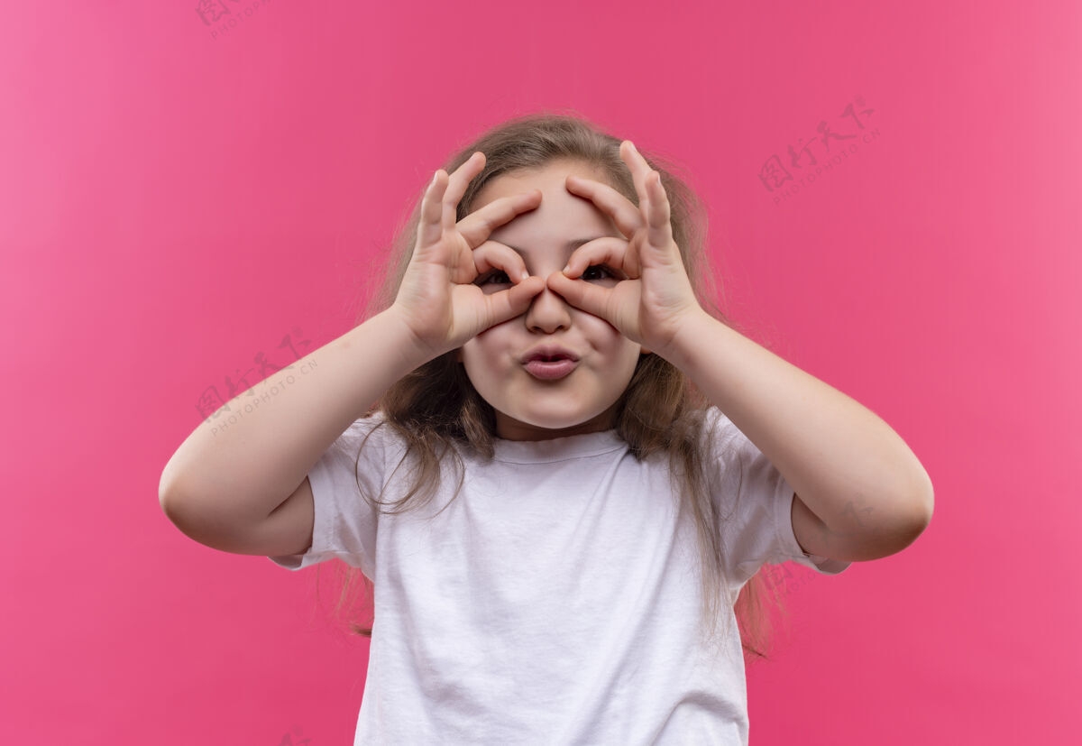 女孩微笑的小女生穿着白色t恤 在孤立的粉色背景上展示表情微笑学校粉色