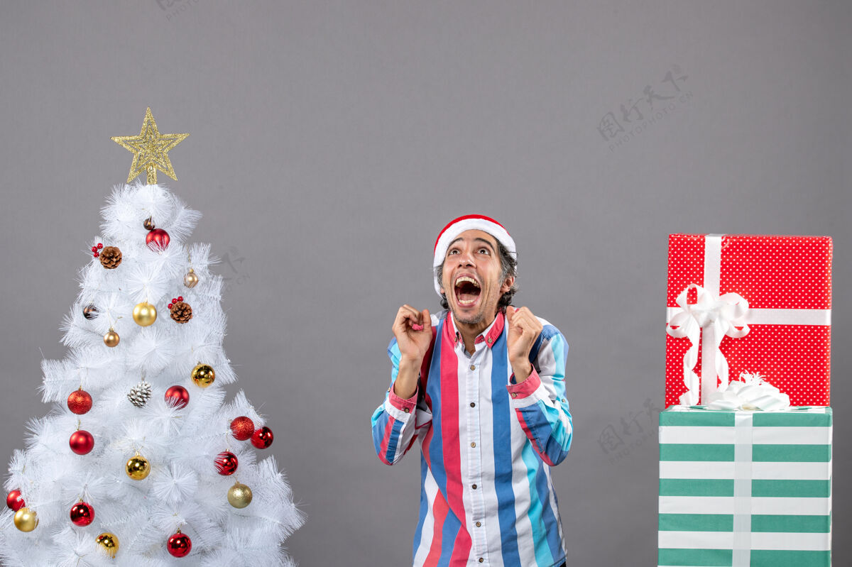 向上前视图兴高采烈的男子抬头看了看白色圣诞树附近快乐人人