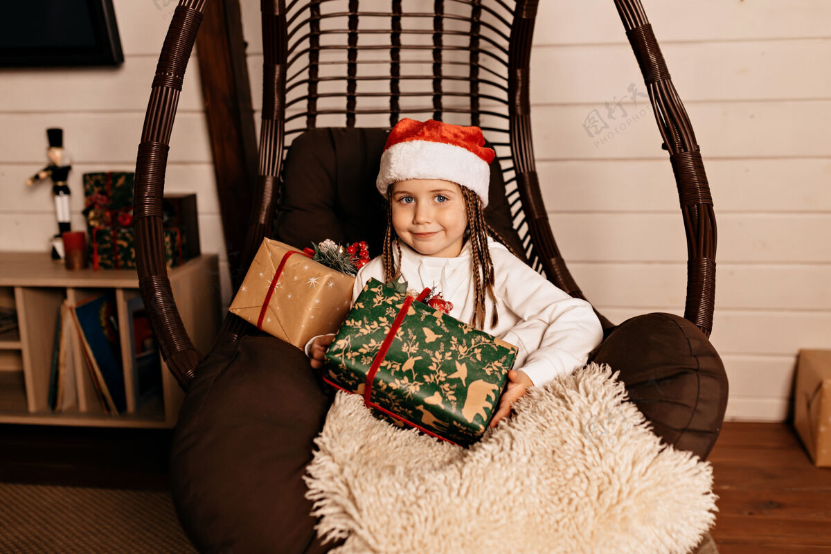 孩子有圣诞礼物的快乐女孩椅子快乐微笑